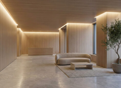 Modern minimalist condo lobby interior featuring warm wood paneling, stone flooring, and elegant seating.