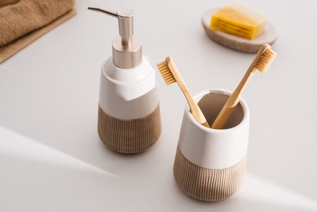 Close up view of liquid soap, toothbrush holder with toothbrushes, towels and dish with soap on